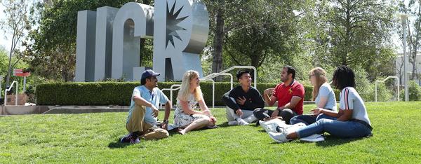 Students sitting in front of UCR Sign