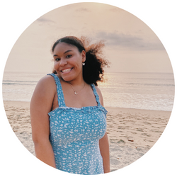 Photo of Mariah vanPutten, a UCR student with dark hair, smiling at the camera with a sandy beach and ocean in the background