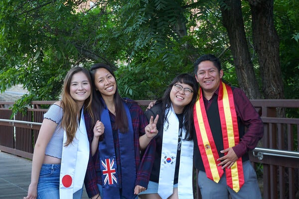 UCR students posing with global graduation sashes