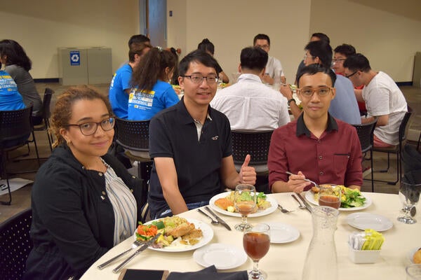 Three people posing with food at UCR Thanksgiving event