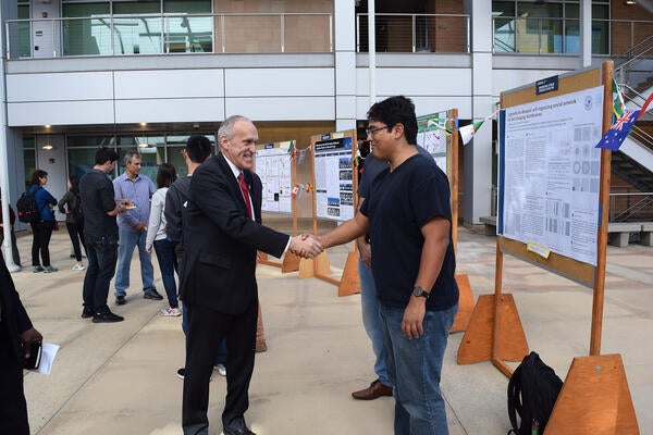 UCR Chancellor Wilcox shaking hands with international scholar at poster fair