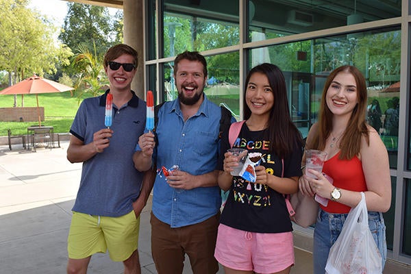 students with popsicles in front of shop