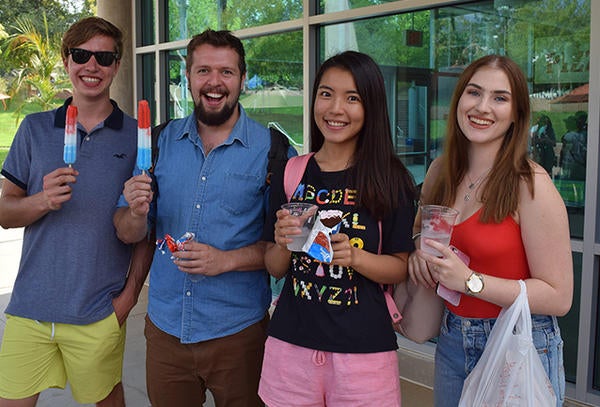 students with popsicles in front of shop