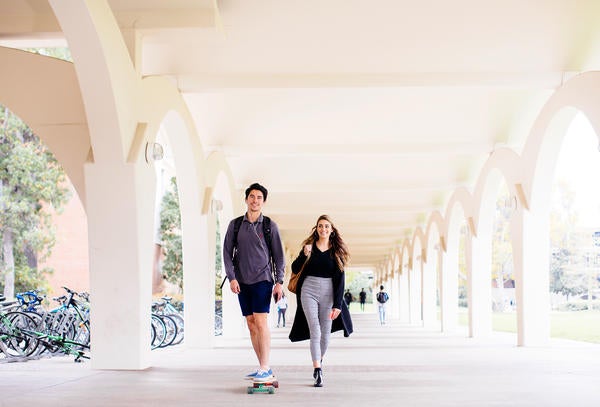 UCR students skateboarding under Rivera Library arches