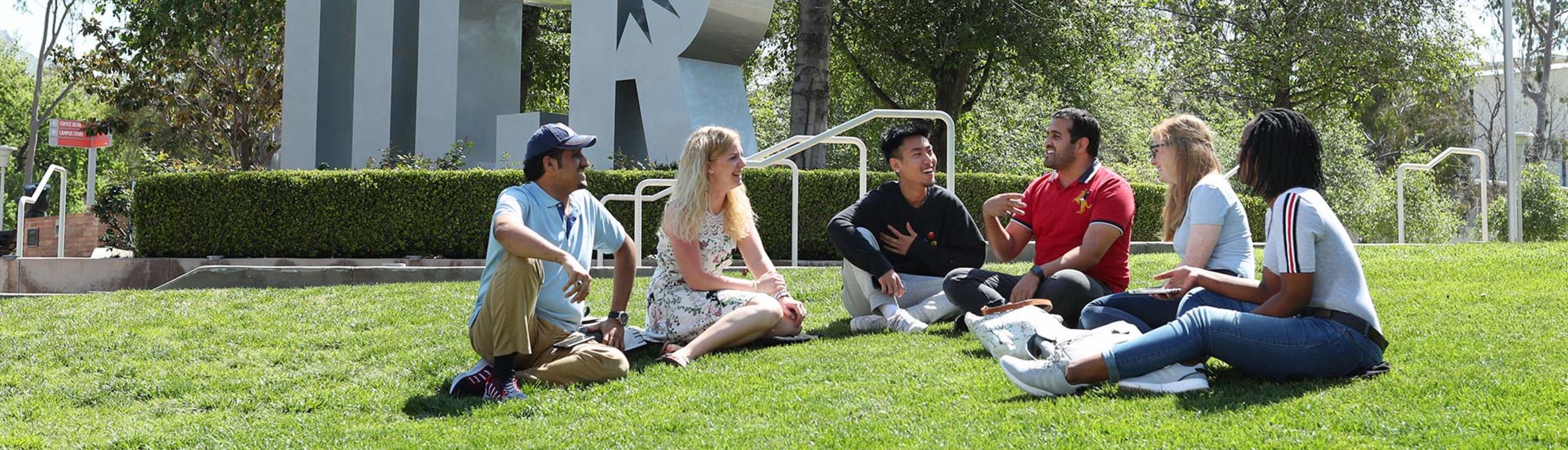 Students sitting in front of UCR Sign